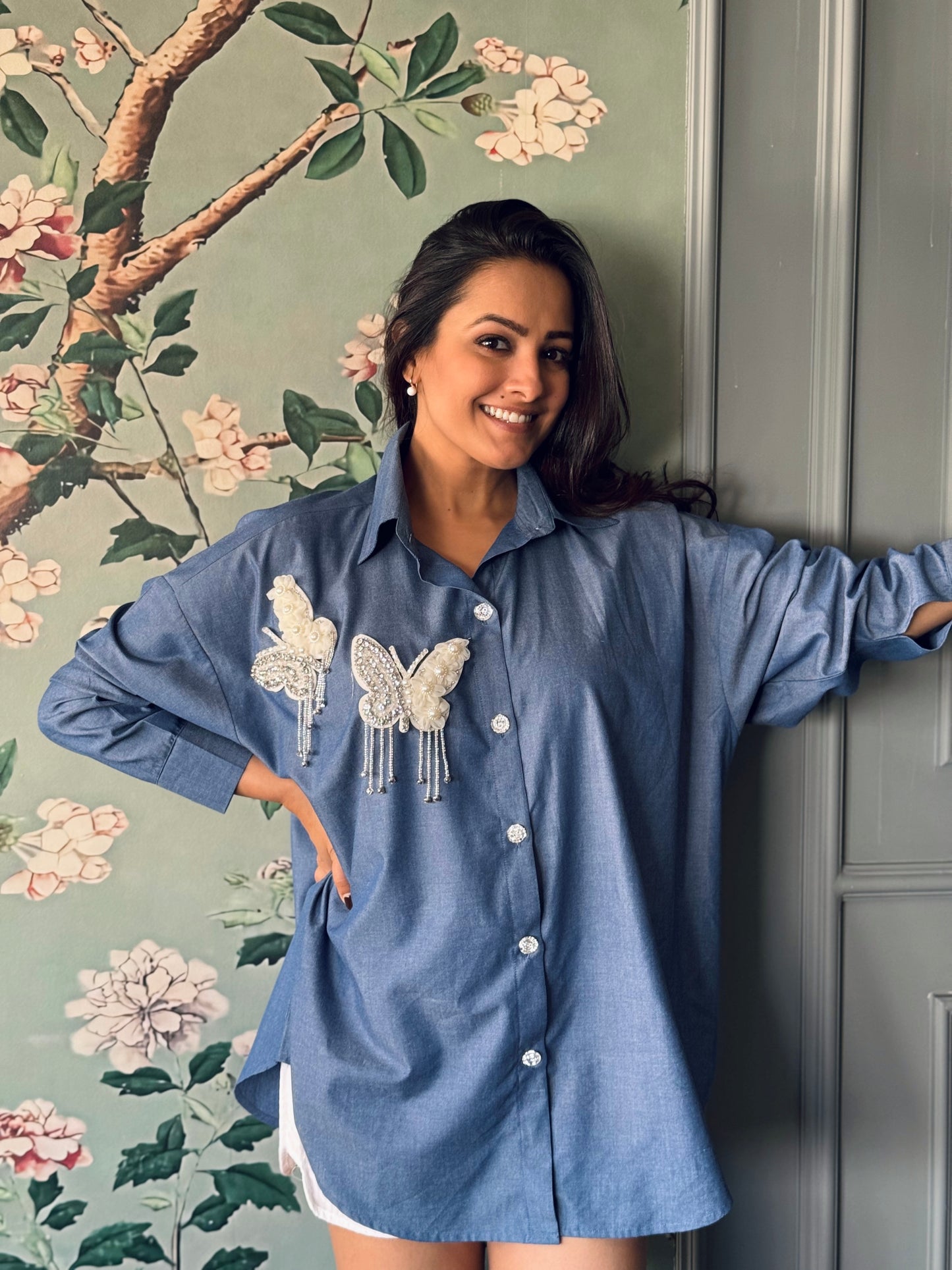 Anita Hassanandani Reddy wearing the Butterfly Dreams Oversized Shirt by Noa - Made with Love, showcasing the front view with butterfly patches embellished with diamonds and pearls.
